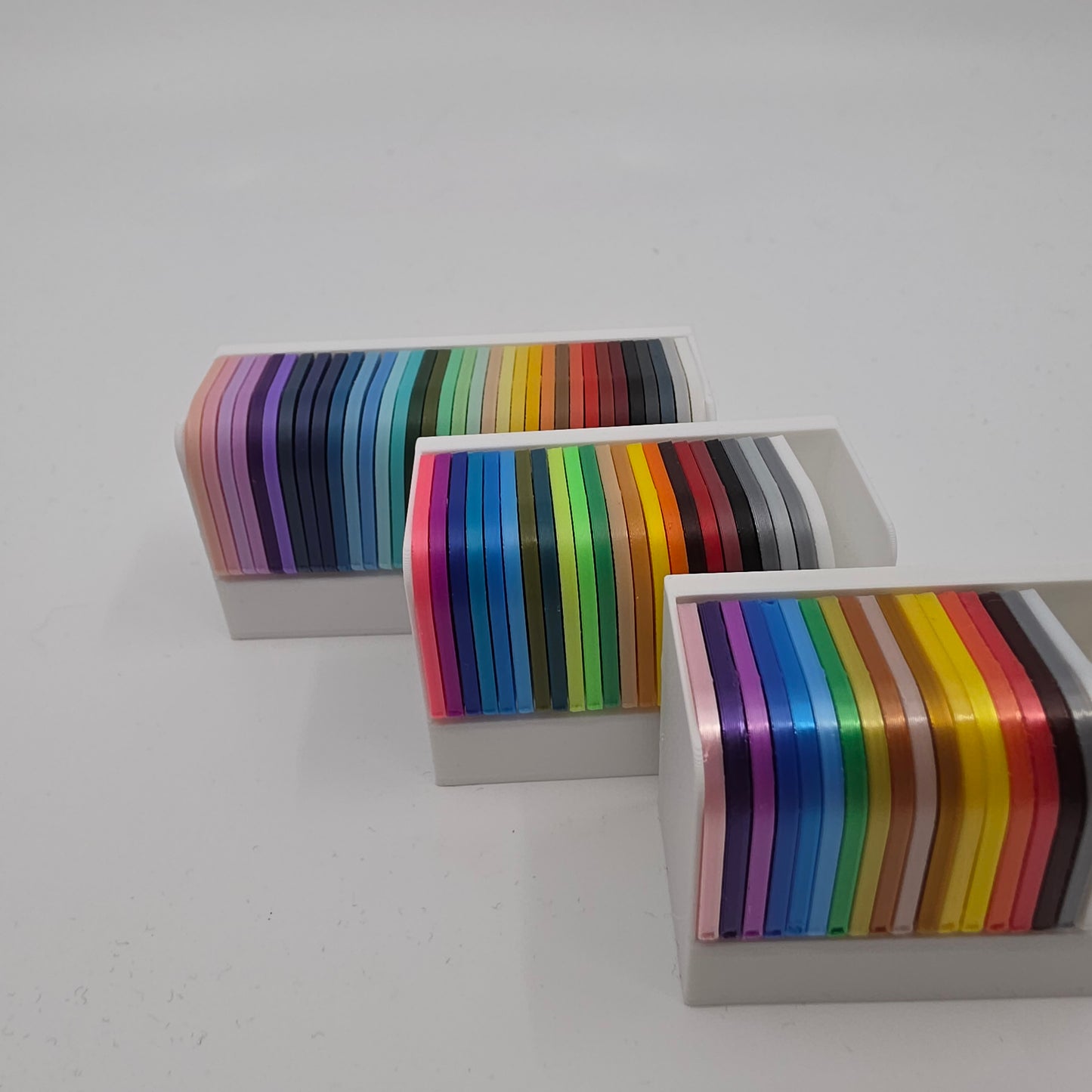 3D printed filament colour sample swatches in organised holders, showcasing a wide range of PLA and PETG colours for 3D printing material selection organised