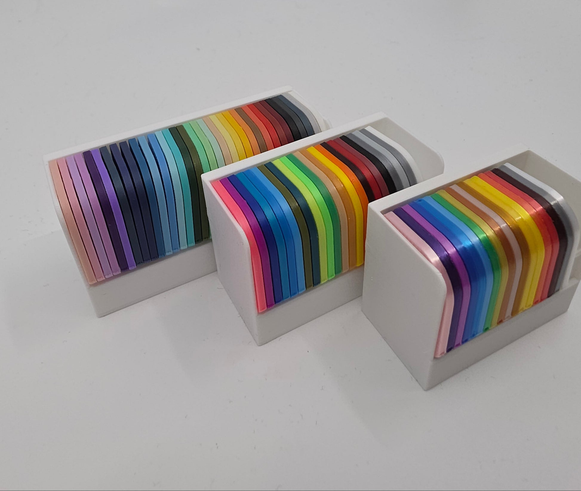 3D printed filament colour sample swatches in organised holders, showcasing a wide range of PLA and PETG colours for 3D printing material selection side angle