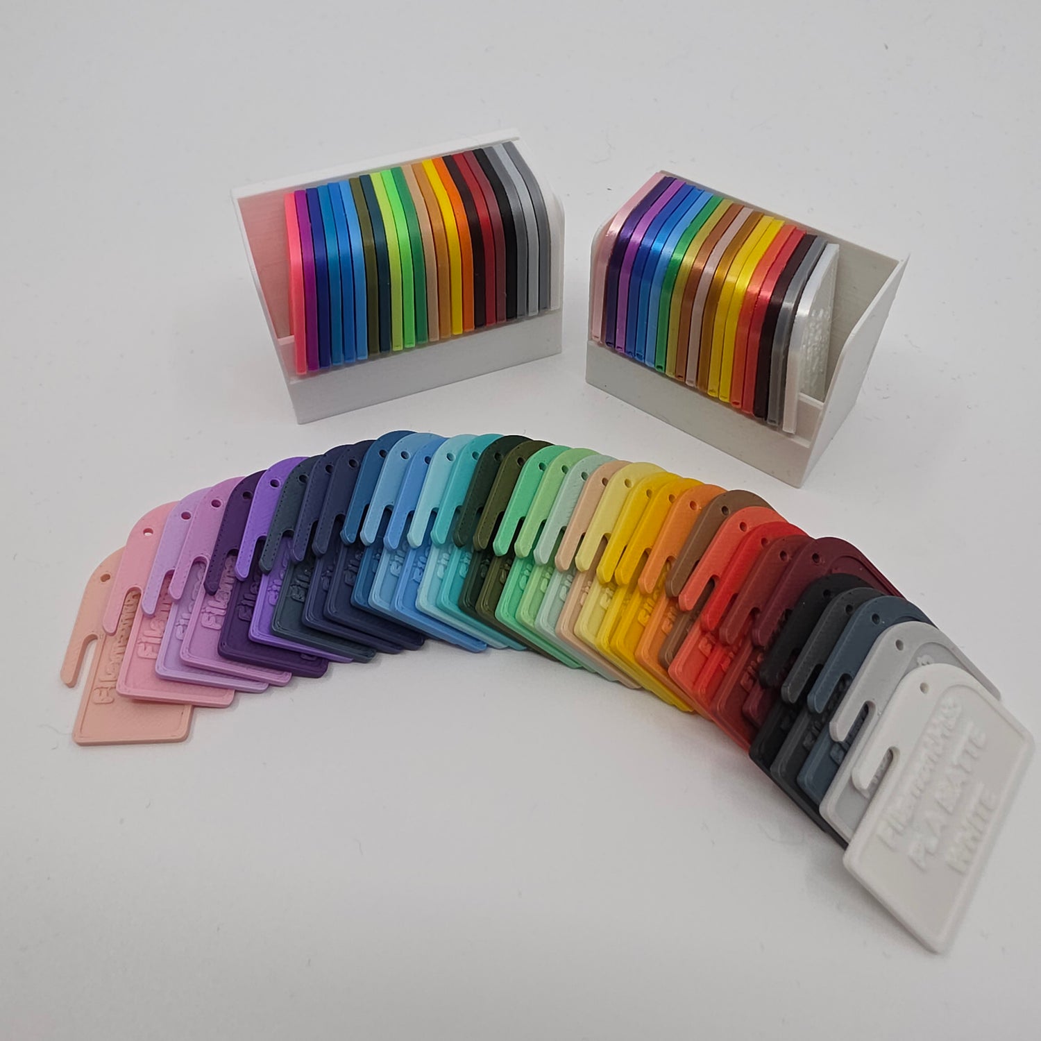 3D printed filament colour sample swatches in organised holders, showcasing a wide range of PLA and PETG colours for 3D printing material selection displaying colours