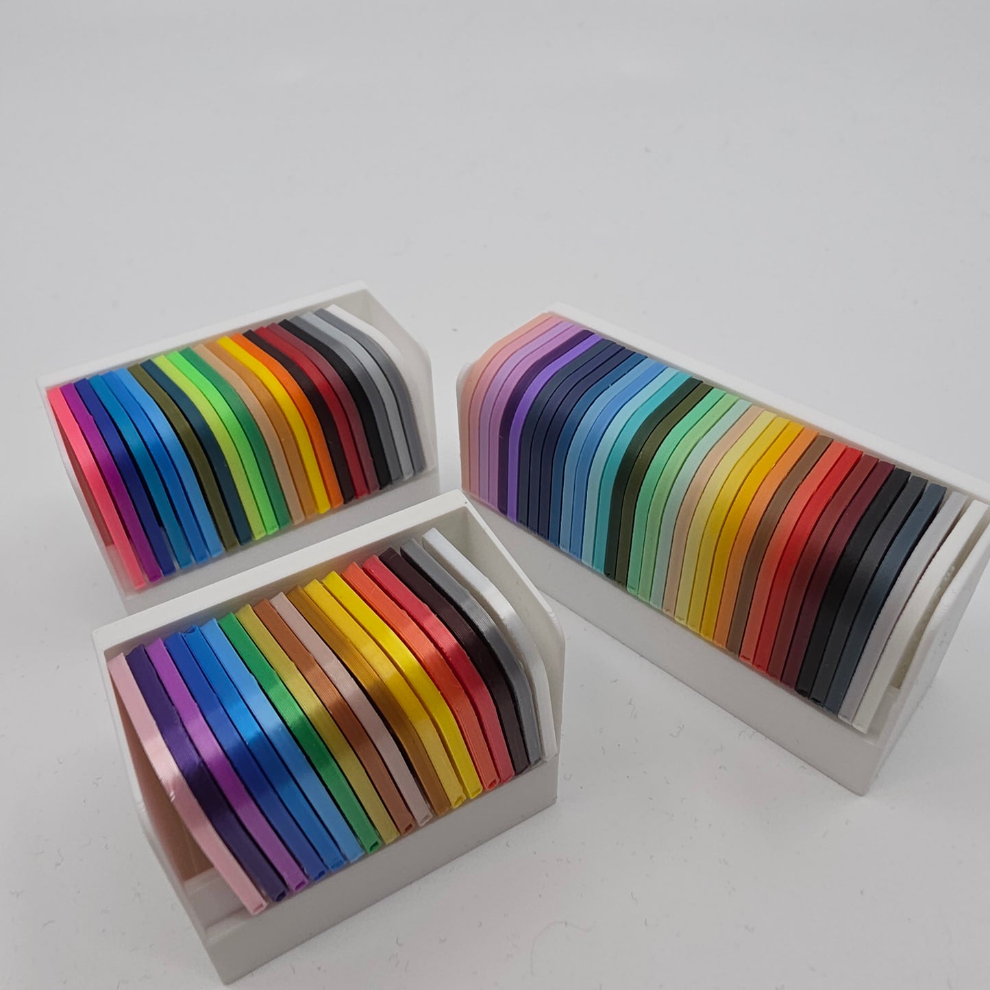 3D printed filament colour sample swatches in organised holders, showcasing a wide range of PLA and PETG colours for 3D printing material selection