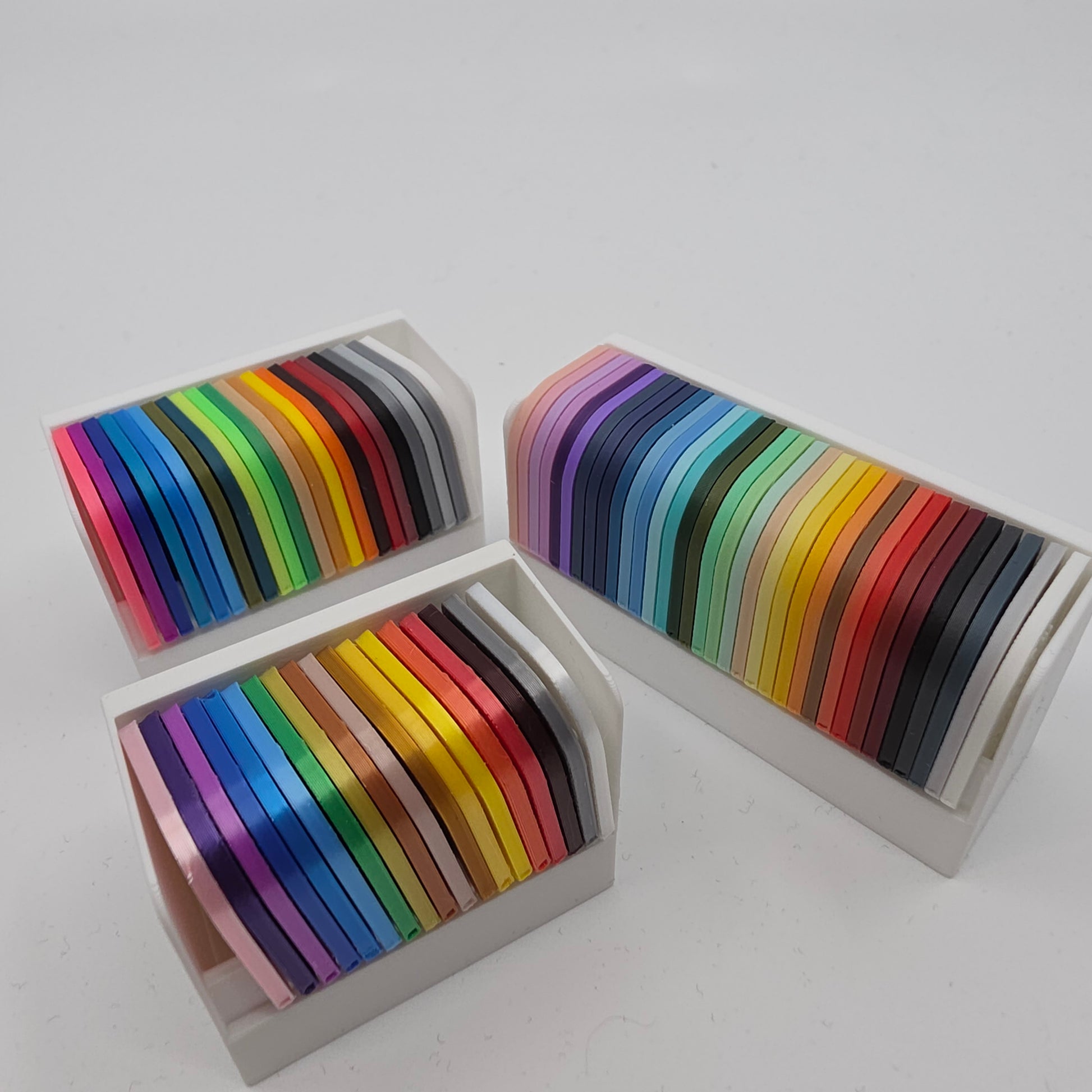 3D printed filament colour sample swatches in organised holders, showcasing a wide range of PLA and PETG colours for 3D printing material selection